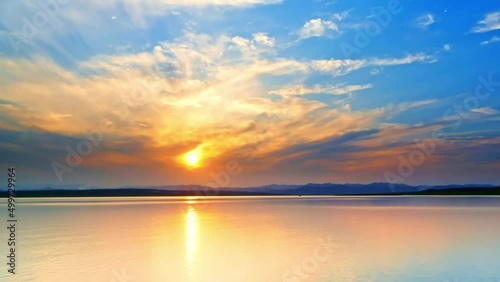 Time lapse of flowing clouds and sunlight refleted onto the sparkling water at sunset photo