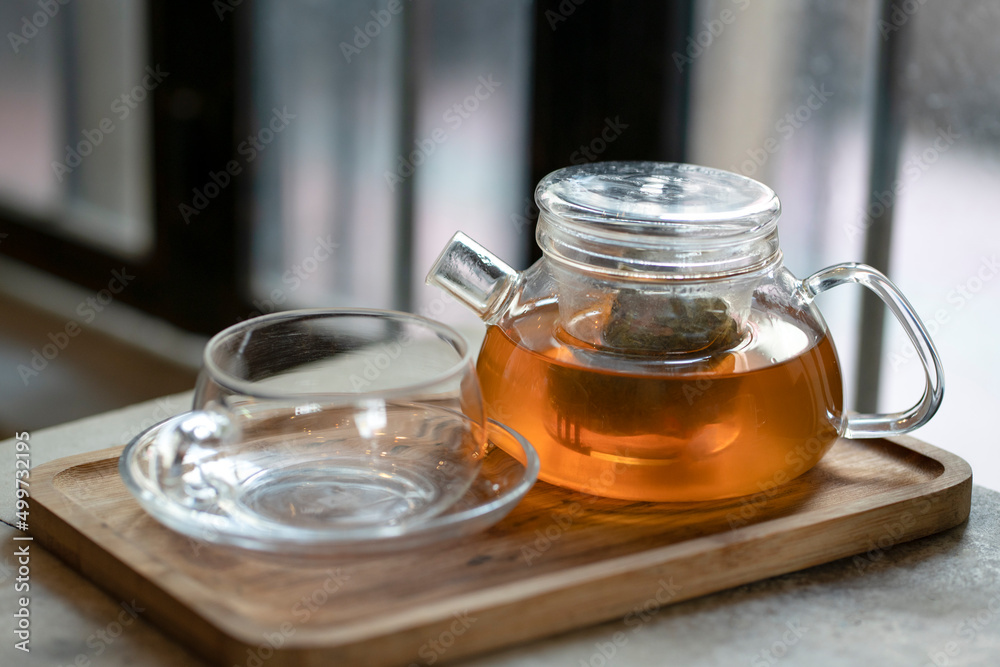 Warm tea in a teapot and cup on a wooden tray. Ready to serve. Warm tea in a teapot and cup on a wooden tray. Ready to serve.