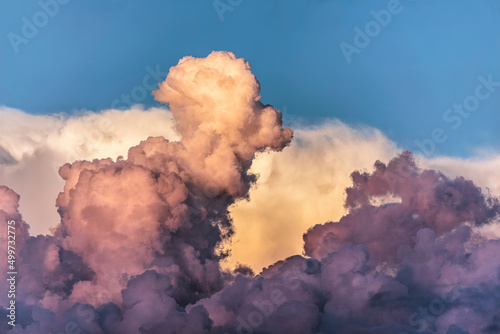Billowing cloud formations display dramatic colorful hues just after sunset backed by a blue sky.