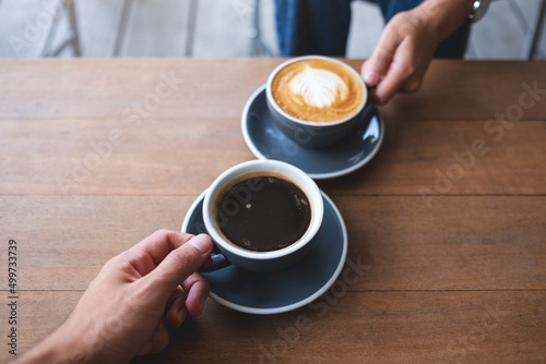 Closeup image of a couple people clinking coffee cups together in cafe