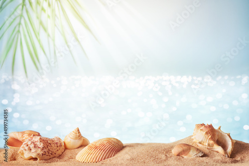 Blurred sea background with palm leaves, sand and seashells. Backdrop for advertising summer travel and sun protection products