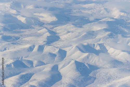 Aerial view of snow-capped mountains and clouds. Winter snowy mountain landscape. Icheghem Range, Kolyma Mountains. Koryak Okrug (Koryakia), Kamchatka Krai, Siberia, Far East Russia. Great background. © Andrei Stepanov