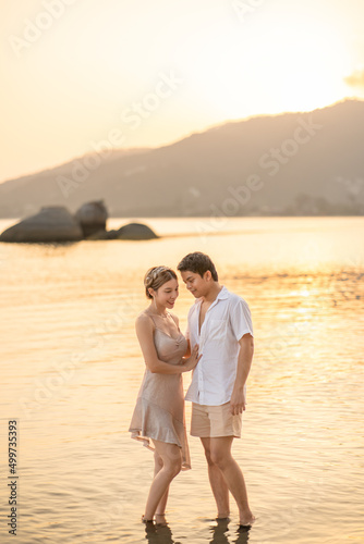 Couple is embracing  and looking each other on the beach at sunset, romantic moment.