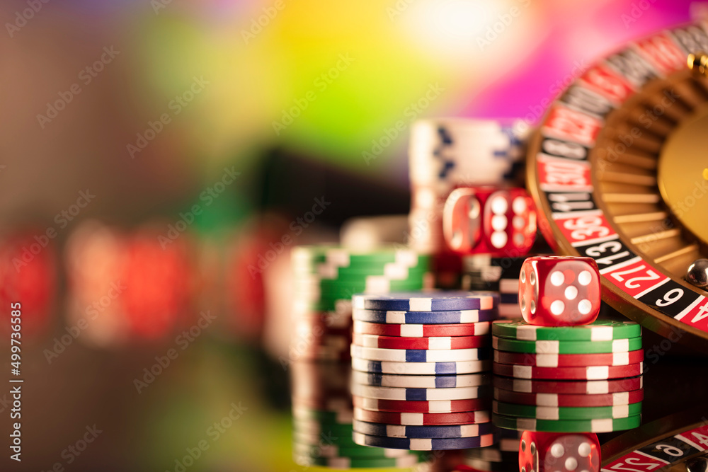Casino theme. Gambling games. Roulette and poker chips on a colorful bokeh background. Casino theme. Gambling games. Roulette and poker chips on a colorful bokeh background.