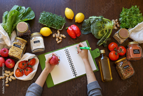 Young Asian woman writes down recipe for a dish in notebook. Zero waste. Vegetarian woman.