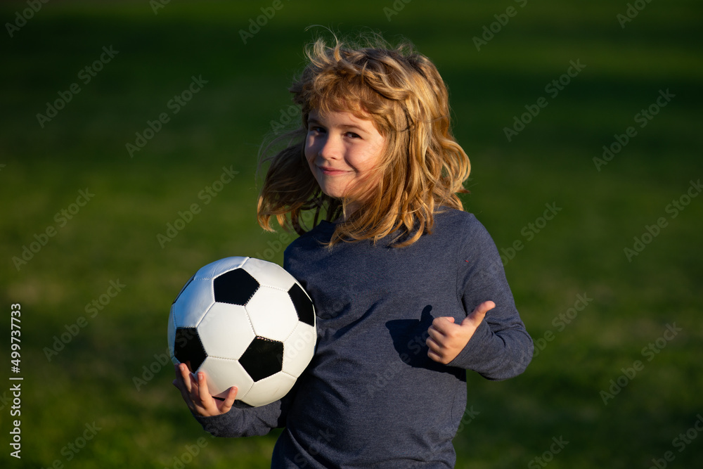 Boy holding soccer ball, close up sporty kids portrait. Young soccer player show thumbs up success sign.