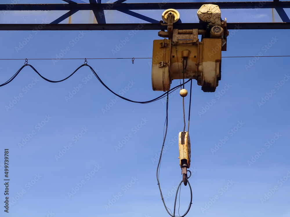 Close up of yellow industrial crane hook (winch) towards blue clear sky. Iron, metal structure. Noblessner, Tallinn, Estonia. Close up of yellow industrial crane hook (winch) towards blue clear sky. Iron, metal structure. Noblessner, Tallinn, Estonia.