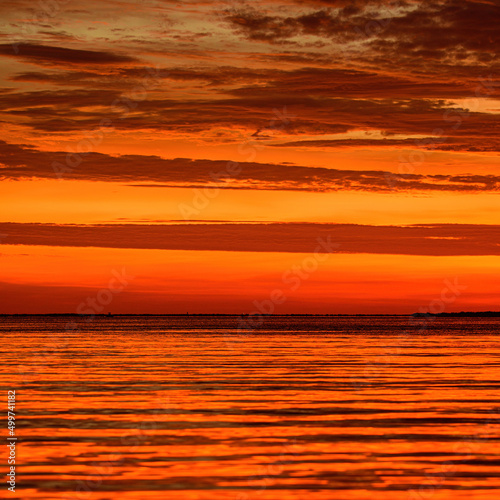 Landscape of sea and tropical beach at sunset or sunrise time for leisure travel and vacation. Reflection of sun in the water and sand on beach.