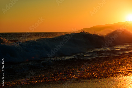 Gold sky and sea water. Sunset at sea landscape. Dramatic sunset sky with clouds. Waves splashes. Dramatic sunset over the sea.