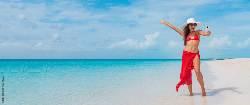 © Maridav - Beach vacation summer woman taking fun phone selfie photo with smartphone. Elegant Asian woman wearing sunglasses doing phone self portrait photo excited in sun on tropical travel holidays