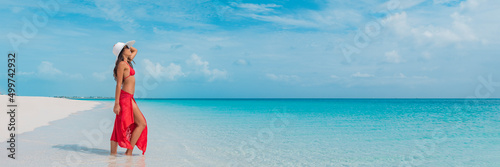 Luxury beach vacation elegant tourist woman walking relaxing in beachwear hat on white sand Caribbean beach. Lady tourist on holiday vacation resort. Banner panorama landscape
