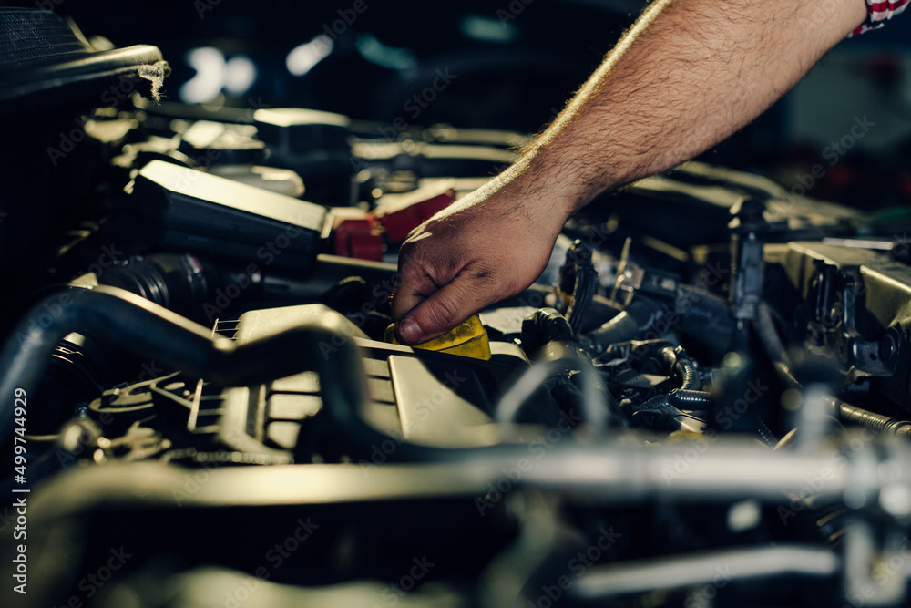 Car mechanic checking oil level in a mechanical workshop