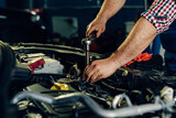 Auto mechanic working on car engine in mechanics garage.