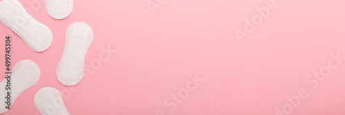 New white panty liners on light pink table background. Pastel color. Closeup. Female daily hygiene. Wide banner. Empty place for text. Top down view. photo