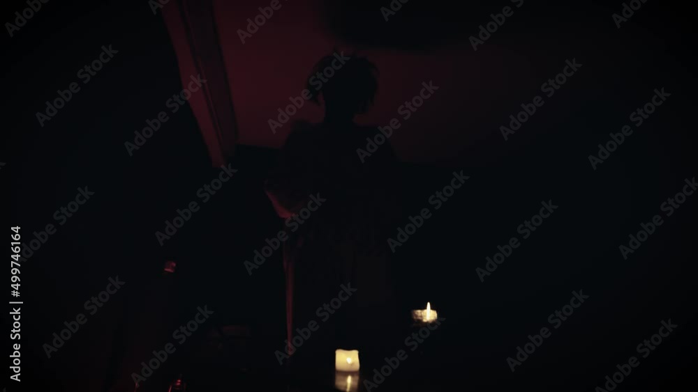 A scary clown, a monster in a dark room with candles in his hands A scary clown, a monster in a dark room with candles in his hands