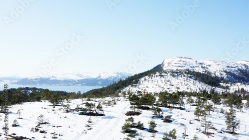 Lateral Aerial View Of Snowy And Greenery Mountains In Blaheia, Norway During Winter photo