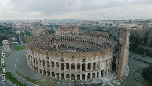 Aerial view in front of the famous Colosseum Amphitheatre, in cloudy Rome city - tilt, drone shot photo