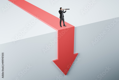 Attractive young european businessman with telescope standing on abstract red arrow falling down cliff. Crisis and failure concept.