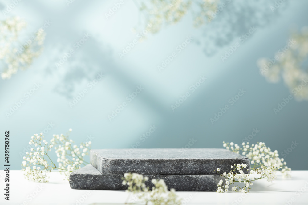 Flat granite pedestal and white flowers on blue background.  Showcase for cosmetic products. Product advertisement. Layout style design. - obrazy, fototapety, plakaty 