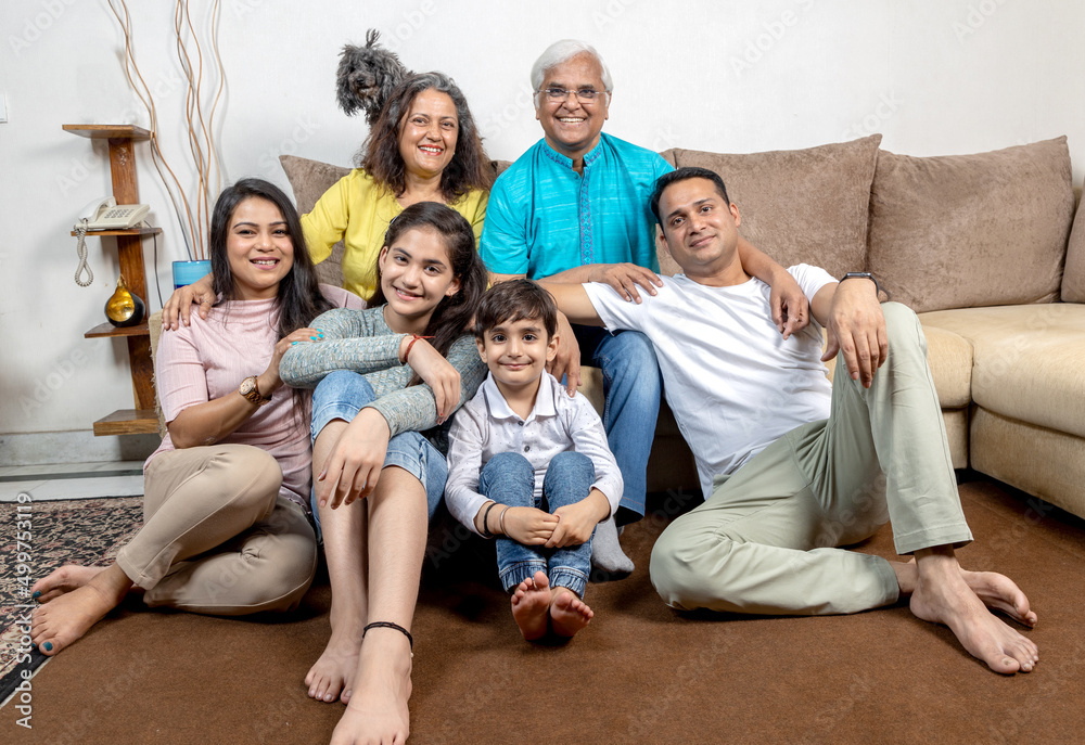 portrait of happy indian family sitting at sofa