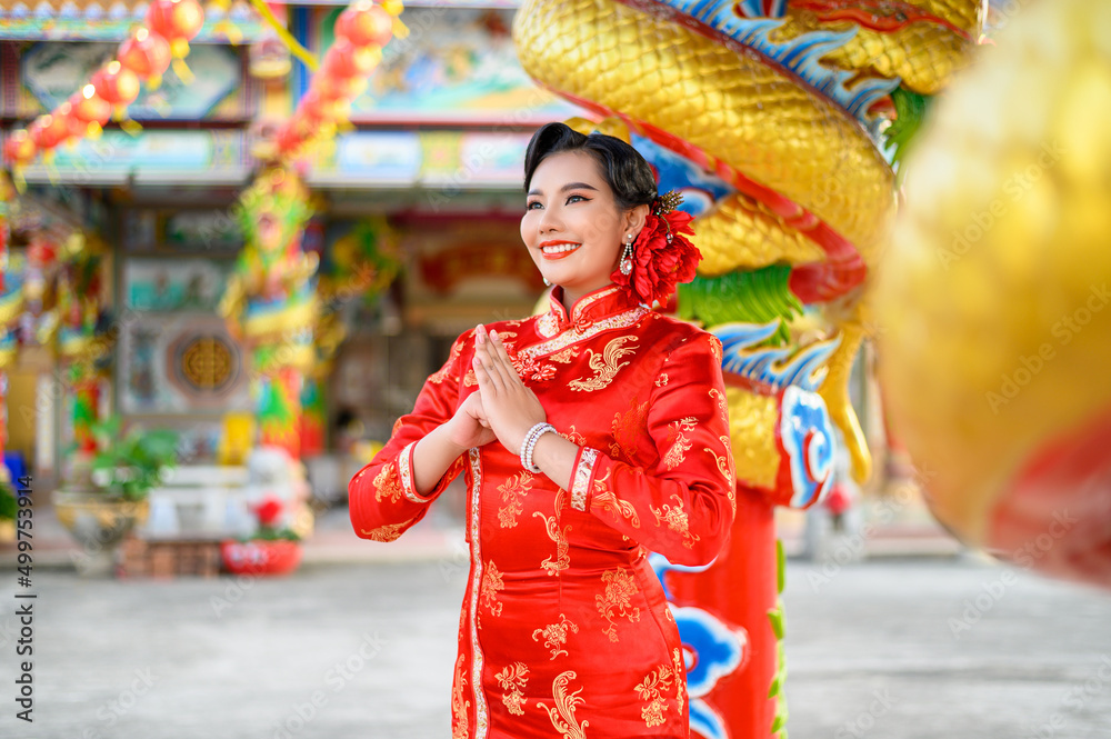 Fototapeta premium Asian beautiful woman wearing a cheongsam poses at shrine on Chinese New Year