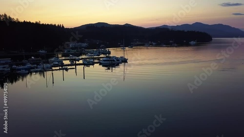 Marina Full of Boats and Seaplanes During Sunset With the Silhouette of the Mountains in the Background in Sechelt Inlet British Columbia Canada - Forward Panning Aerial Shot photo