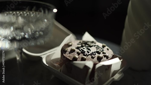 Chocolate bento cake in eco box with wooden spoon. White candle and chmpagne glasses on luxury marble table photo