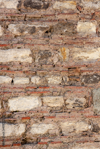 Old wall of rows of large blocks and rows of small bricks. Vertical photo.