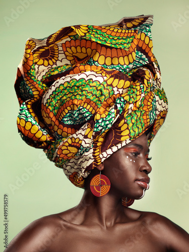 Life is better in colour. Studio shot of a beautiful young woman wearing a traditional African head wrap against a green background.