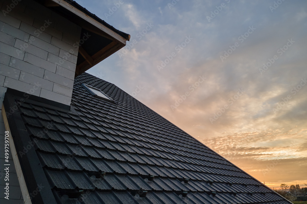Closeup of house roof top covered with metallic shingles.Tiled covering of building Closeup of house roof top covered with metallic shingles.Tiled covering of building