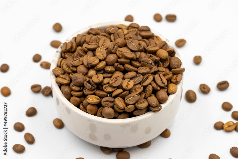 Coffee beans isolated on a white background. Full of coffee beans in a marble plate. Close-up. Coffee beans isolated on a white background. Full of coffee beans in a marble plate. Close-up.