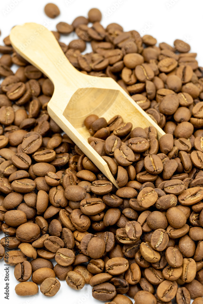 Fototapeta premium Coffee beans isolated on a white background. Full of coffee beans in a wooden spoon. Close-up.