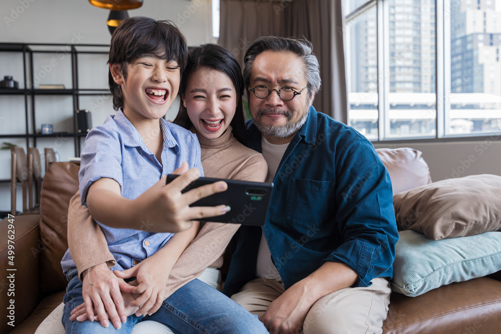 Family smiling at camera. Happy family taking a selfie, smiling at a phone at home. Family smiling at camera. Happy family taking a selfie, smiling at a phone at home.
