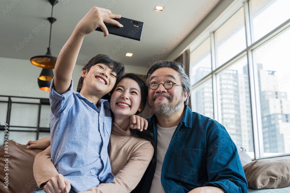 Family smiling at camera. Happy family taking a selfie, smiling at a phone at home