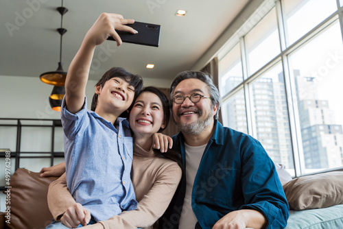 Family smiling at camera. Happy family taking a selfie, smiling at a phone at home