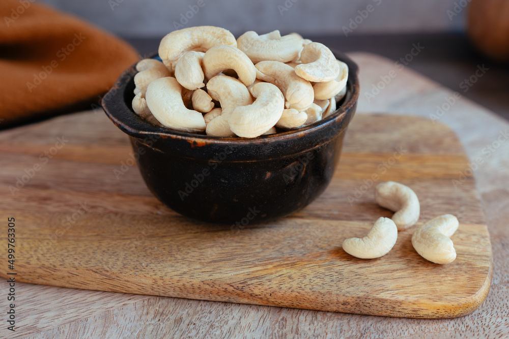 Black bowl with cashew nuts and dried fruit on wooden board Black bowl with cashew nuts and dried fruit on wooden board