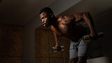 Attractive african american man doing arm exercises with dumbbells. 