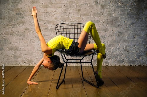 Young gymnast girl stretching and training. Sport and healthy lifestyle concept. Stretching exercises in a chair