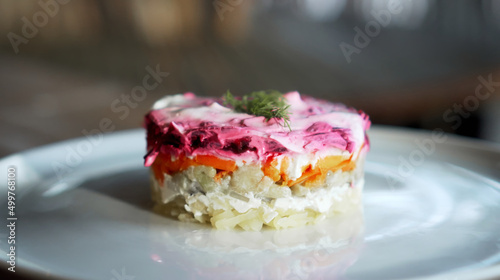Traditional Russian salad with beetroot and herring vegetables, lying on a wooden table in a white plate
