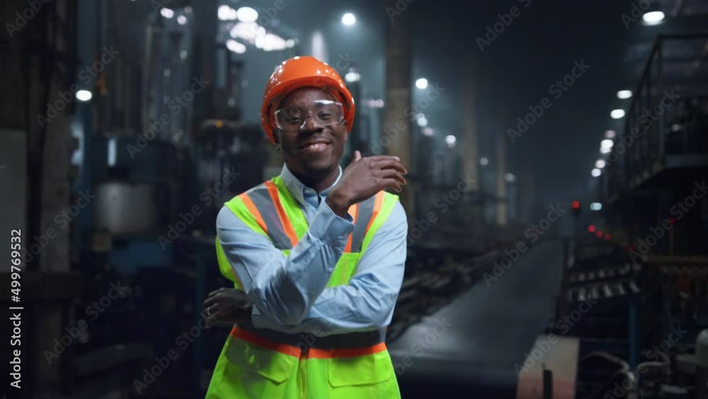 Happy supervisor smiling camera wearing safety uniform at modern facility.
