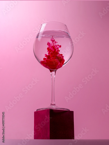 Wine glass on a cube with red dye dissolving in water