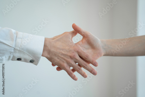 Businessmen shake hands to each other after successful meeting on white background. People come to agreement at work in office room close view © Grustock