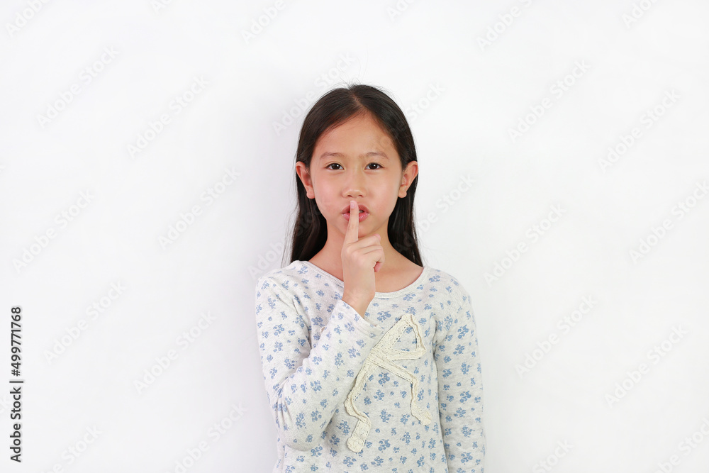 Portrait of Asian girl child with finger up to lips for making a quiet gesture isolated on white background. Kid showing shh sign. Portrait of Asian girl child with finger up to lips for making a quiet gesture isolated on white background. Kid showing shh sign.
