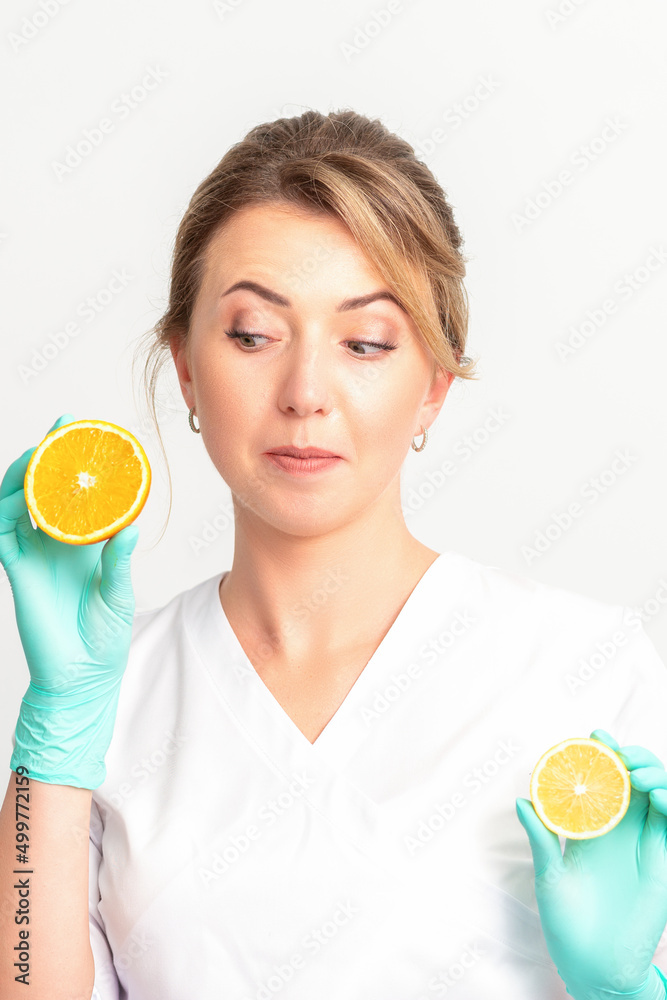 Smiling female nutritionist holding a sliced orange, looking at camera over white background, healthy diet concept Smiling female nutritionist holding a sliced orange, looking at camera over white background, healthy diet concept