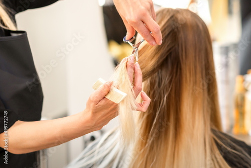 Beautiful young blonde woman with long straight blonde hair getting a haircut at the hairdresser salon