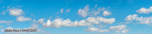 Banner with panoramic view over deep blue clean sky with illuminated clouds as a background.