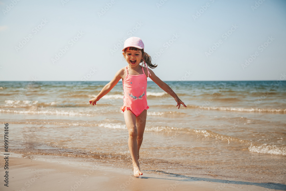 Adorable little girl having fun on the beach of a Baltic sea
