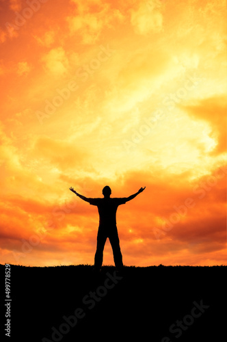 man silhouette with open arms in front of a sunset sky