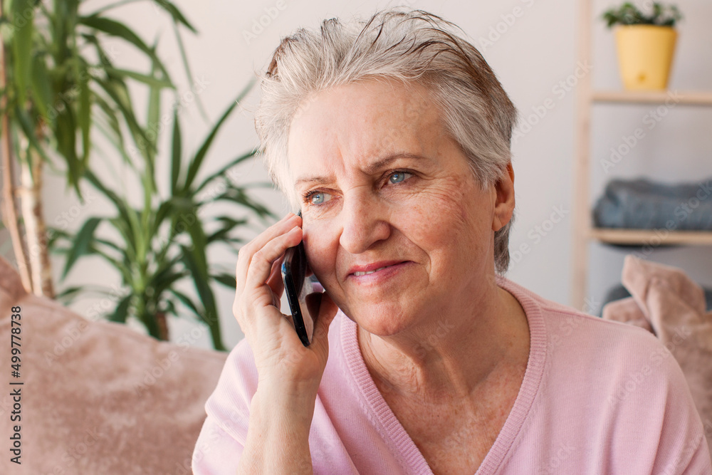 Mature woman sitting on sofa at home with mobile phone Mature woman sitting on sofa at home with mobile phone