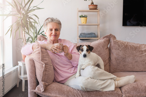 mature older adult grey-haired woman drinking coffee relaxing on sofa at home